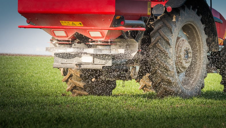 A tractor applying fertiliser on pasture